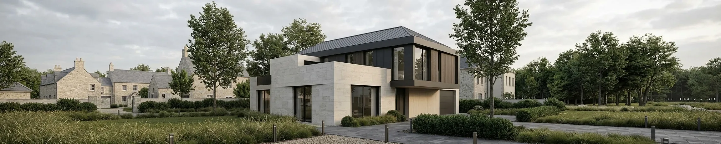 A contemporary house in pale coursed stone with a dark standing-seam roof and a timber-clad upper bay, set behind meadow grasses with older stone buildings and mature trees beyond.