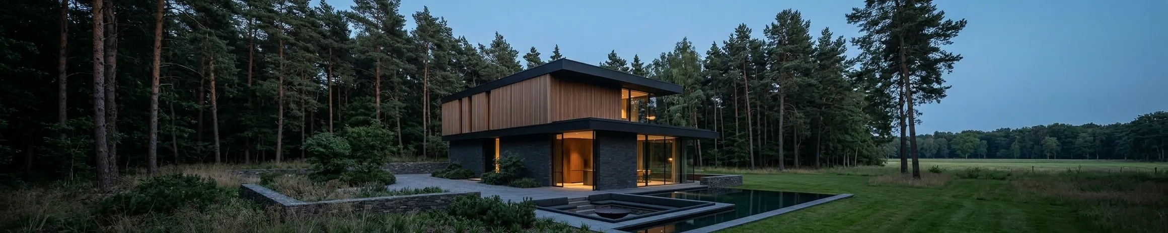 A two-storey house of timber and dark slate standing among tall pines, with lawn and a pool in front of it.